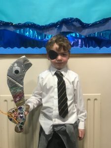 Young boy with sunglasses holding a colorful fish craft, standing indoors at Inchmarlo.