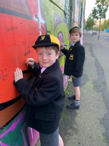 Two children drawing on colorful mural at Inchmarlo School playground.