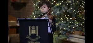 Young musician playing piano at Inchmarlo estate during festive season.