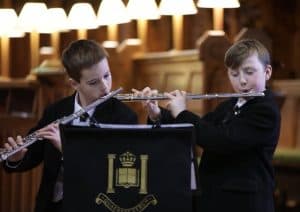 Two boys playing flutes at a school music event.