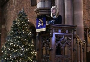 Elegant speaker at Inchmarlo Christmas event with decorated tree and historic venue.