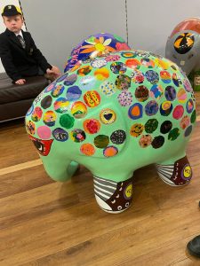 Vibrant pig sculpture with colorful stickers, art display at Inchmarlo.