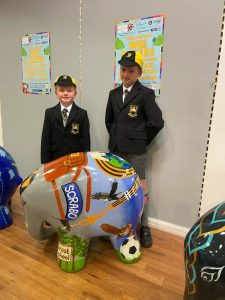 Two children in school uniforms with a colorful globe sculpture.