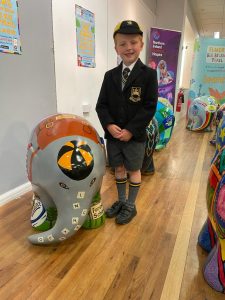 Young boy smiling with school mascot statue.