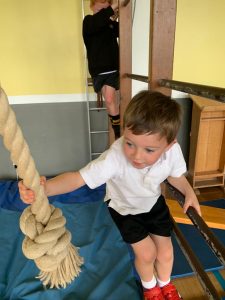 Child climbing rope at Inchmarlo activity center, engaging in active play and development.