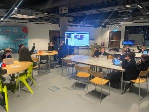 A modern, vibrant classroom with students engaged in learning using digital screens.