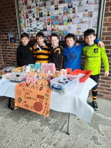 Group of children at Inchmarlo fundraising event with baked goods and donations.