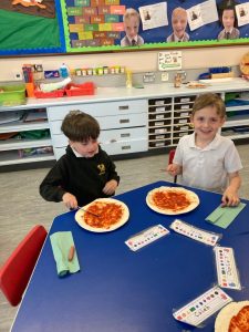 Two children enjoying pizza at school table in classroom.