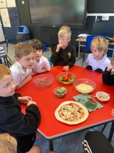 Children enjoying pizza and snacks at Inchmarlo School, promoting student socialization and learning.