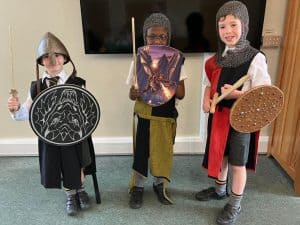 Children in medieval costumes with shields and swords at Inchmarlo school event.