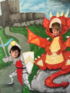 Two children dressed as a knight and a dragon, playfully imagined in a colorful mural.