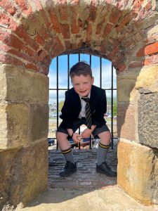 Child peeking through historic stone window at Inchmarlo estate.