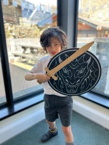 Young boy in medieval costume with shield and sword indoor, promoting family-friendly activities at Inchmarlo.