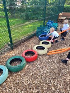 Children enjoying outdoor play with tires and equipment at Inchmarlo.