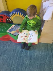 Young child reading colorful storybook at Inchmarlo childcare center, engaging educational environment.