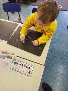 Child drawing with chalk at Inchmarlo, engaging in creative activities in a nurturing environment.