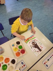 Young child painting colorful artwork with paints and brushes.