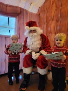 Santa with two children holding gifts at Inchmarlo holiday event.