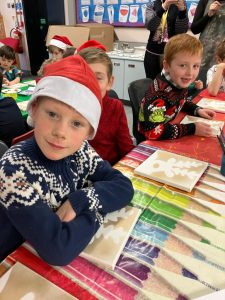 Children in festive sweaters and Santa hats enjoying holiday activities.