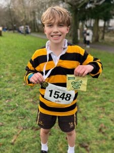 Happy boy with race bib smiling outdoors at Inchmarlo Youth Run event.