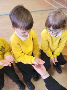 Three children in yellow uniforms receiving a hand massage at Inchmarlo School.