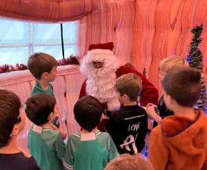 Children meeting Santa Claus at Inchmarlo estate during holiday season, festive decorations and Christmas tree.