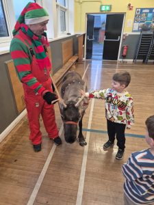 Children and staff interacting with a donkey during a holiday event.