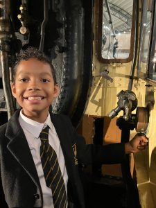 Young boy in school uniform at Inchmarlo estate with historic machinery.