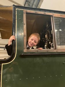 Child smiling through train window, enjoying a scenic ride at Inchmarlo.