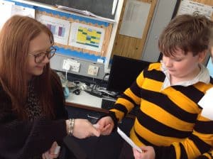 Young girl and teacher working with a paper document in classroom.