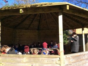 Outdoor wooden gazebo with children playing under shaded area.