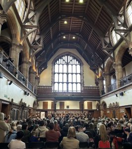 Impressive historic parish church interior with wooden vaulted ceiling and large stained glass window.