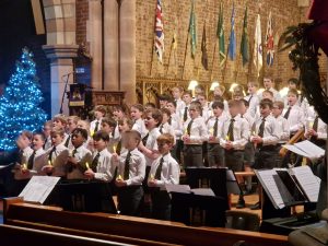Young children singing Christmas carols at Inchmarlo with festive decorations and a Christmas tree.