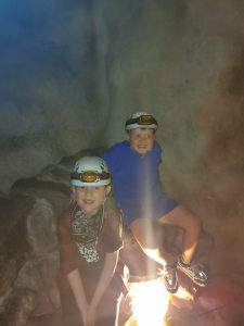 Children exploring caves at Inchmarlo estate in Scotland with headlamps and outdoor gear.