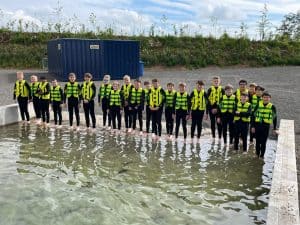 Group of people standing in water at Inchmarlo estate, demonstrating environmental or educational activities.