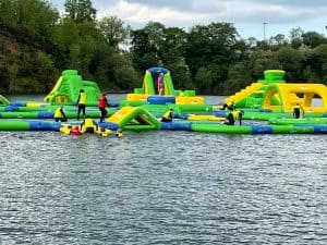 Vibrant inflatable waterpark on a lake with children playing, perfect for outdoor family activities.