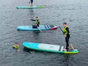 Kids and adults enjoying paddleboarding at Inchmarlo, outdoor water activities in a scenic setting.