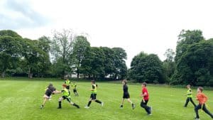Children playing football on lush green field at Inchmarlo. Outdoors activity and family fun in scenic countryside setting.