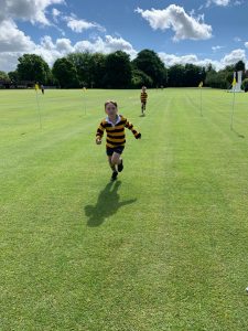 Young child running on the golf course greens during a sunny day.
