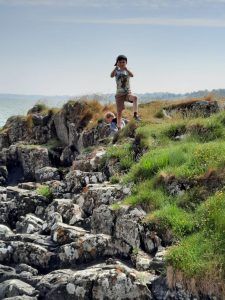 Children exploring rugged coastline at Inchmarlo in Scotland, highlighting outdoor adventure.