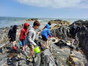 Children exploring rocky shoreline at Inchmarlo estate. Family-friendly outdoor activities near Aberdeen.