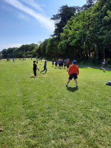 A vibrant scene of people playing golf on a lush, sunny course surrounded by trees.