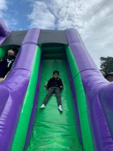 Child sliding on colorful inflatable slide at Inchmarlo outdoor play area.
