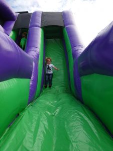 Children enjoying an inflatable slide at Inchmarlo outdoor activity center.
