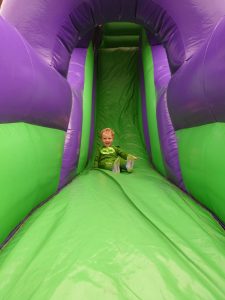 Child enjoying a colorful inflatable slide at Inchmarlo outdoor activity park.