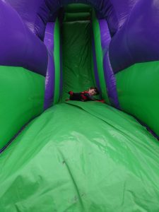 Children enjoying a large inflatable slide at Inchmarlo outdoor activity center.