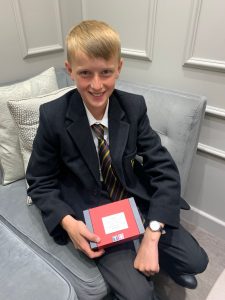 Young boy in school uniform holding a plaque or award at Inchmarlo.