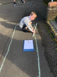 Young boy drawing on pavement with chalk at Inchmarlo outdoor play area.
