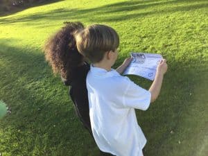Child reading map outdoors on lush green lawn at Inchmarlo estate.