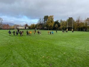 Wide view of Inchmarlo sports field with children playing football in lush green grass.